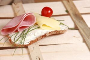 una fetta di pane con formaggio, prosciutto e rosmarino