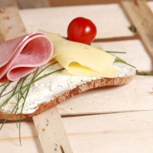 una fetta di pane con formaggio, prosciutto e rosmarino